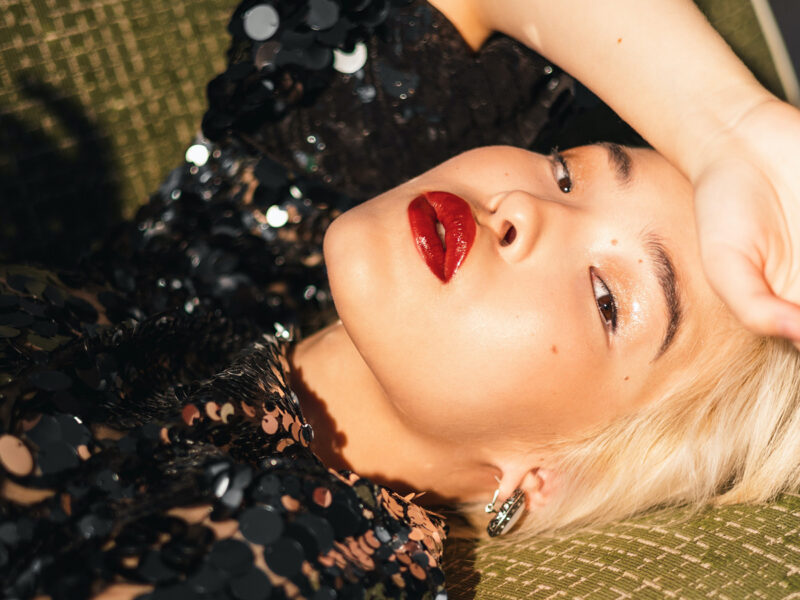 woman laying on couch with black sequinned dress and bold, red lipstick